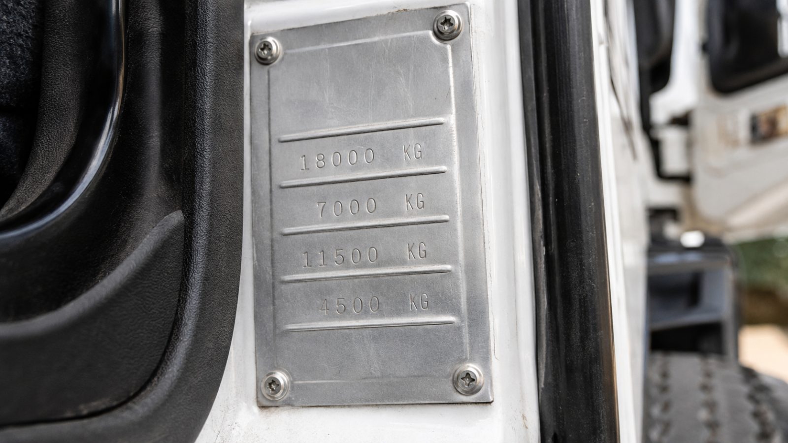 Close-up of truck compliance plate inside door frame showing gross vehicle mass figure