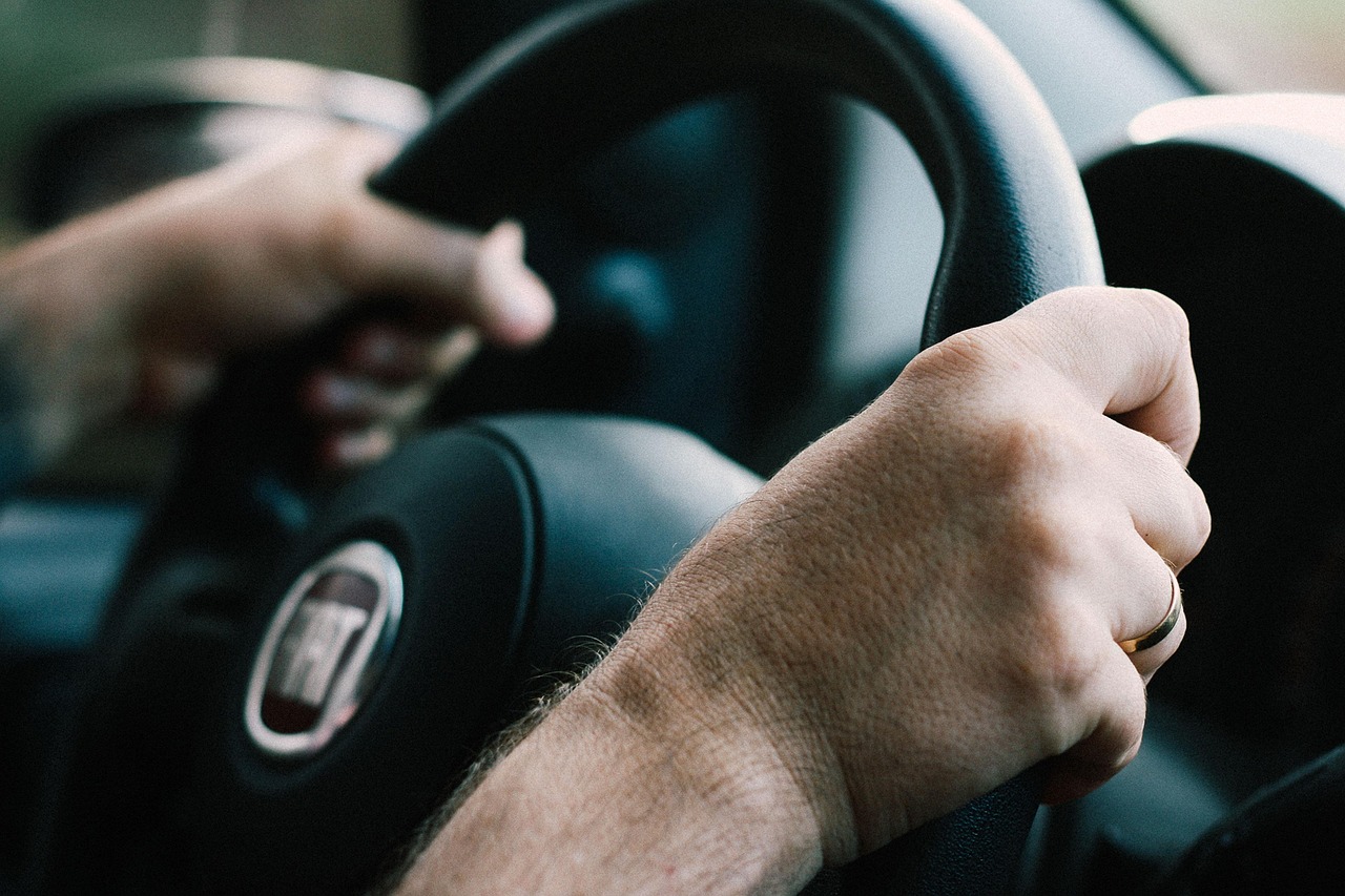 Driver sitting in car with door open, hand on key, listening, with engine bay open