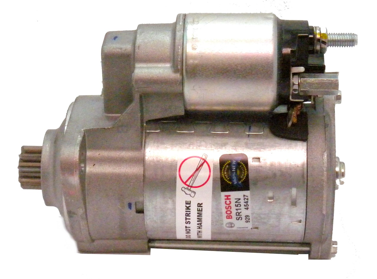 Starter motor removed from car sitting on a workbench with solenoid and mounting flange visible