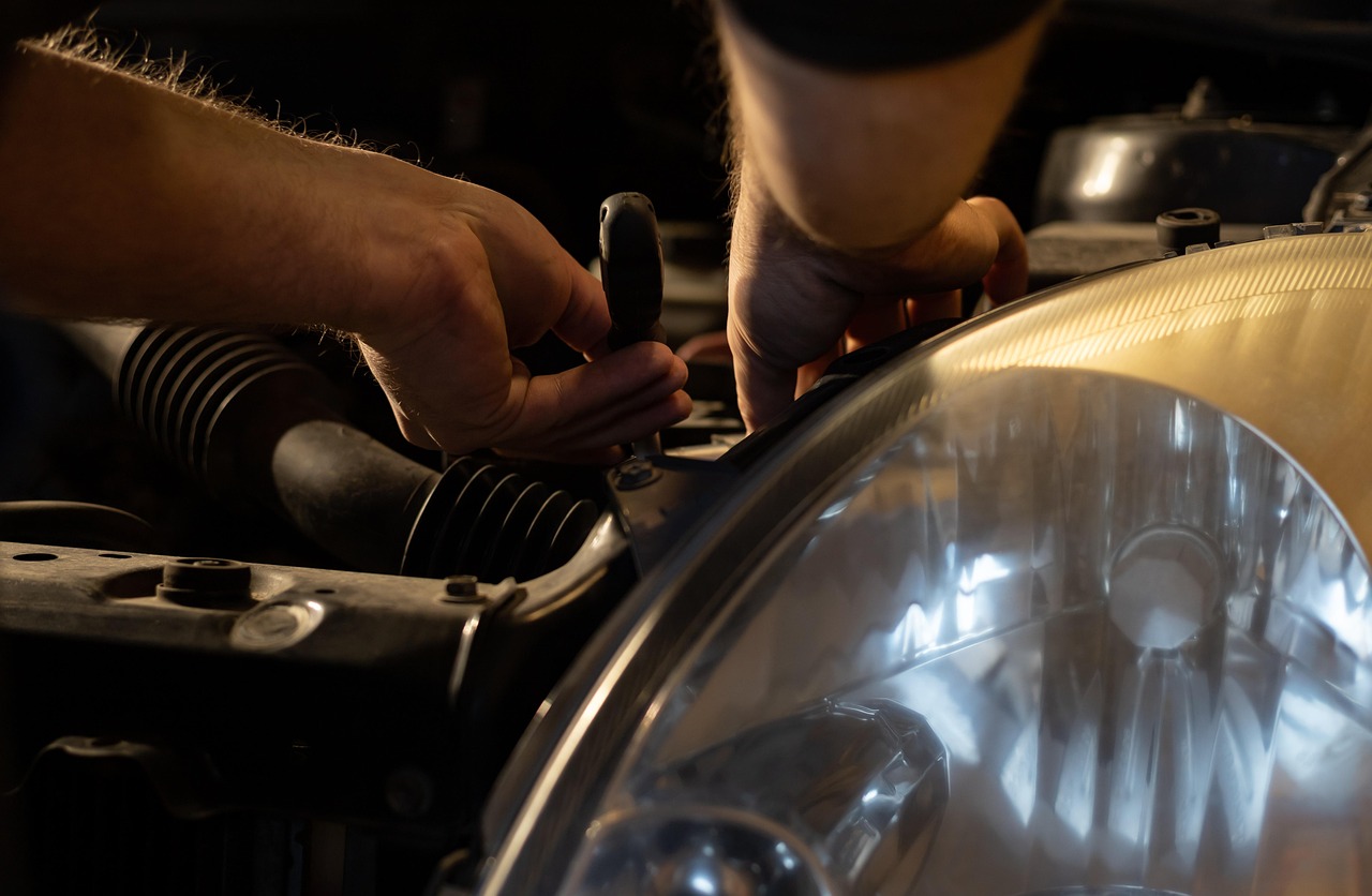Mechanic using a multimeter to test a starter feed cable in an engine bay